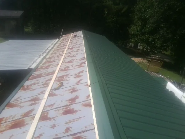 Old rusted panels beside newly installed green metal roofing — Wind Damage Roof Repair by Roofing Brothers in Hillsboro