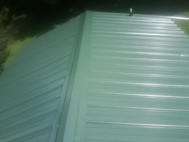 New green metal panels meeting at the ridge of a roof — Flat Roof Repair work by our crew in Hillsboro