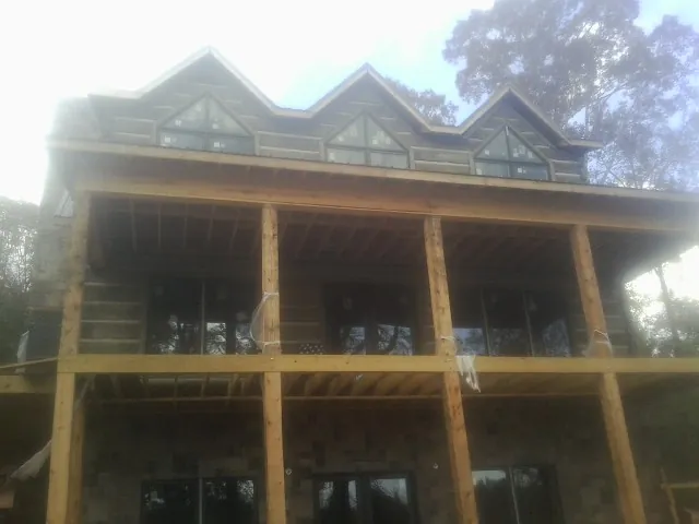 Dormers and porch framing on a large log home under construction — Roof Coating work by our crew in Hillsboro